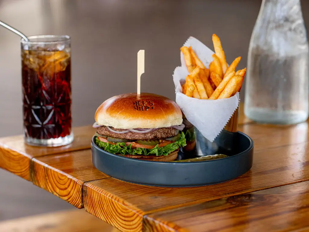 Close-up of a menu featuring a burger and fries at Hef's Hut, showcasing classic American comfort food in a casual dining setting.