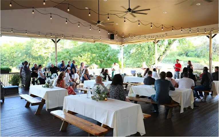 Outdoor wedding celebration at Hef's Hut patio in Vernon, NJ, featuring multiple decorated tables, guests dining and mingling under string lights in a festive atmosphere.