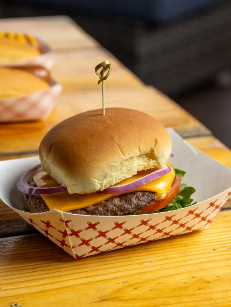 A juicy Hef&rsquo;s Hut cheeseburger photographed up close, showing the melted cheese and fresh toppings.
