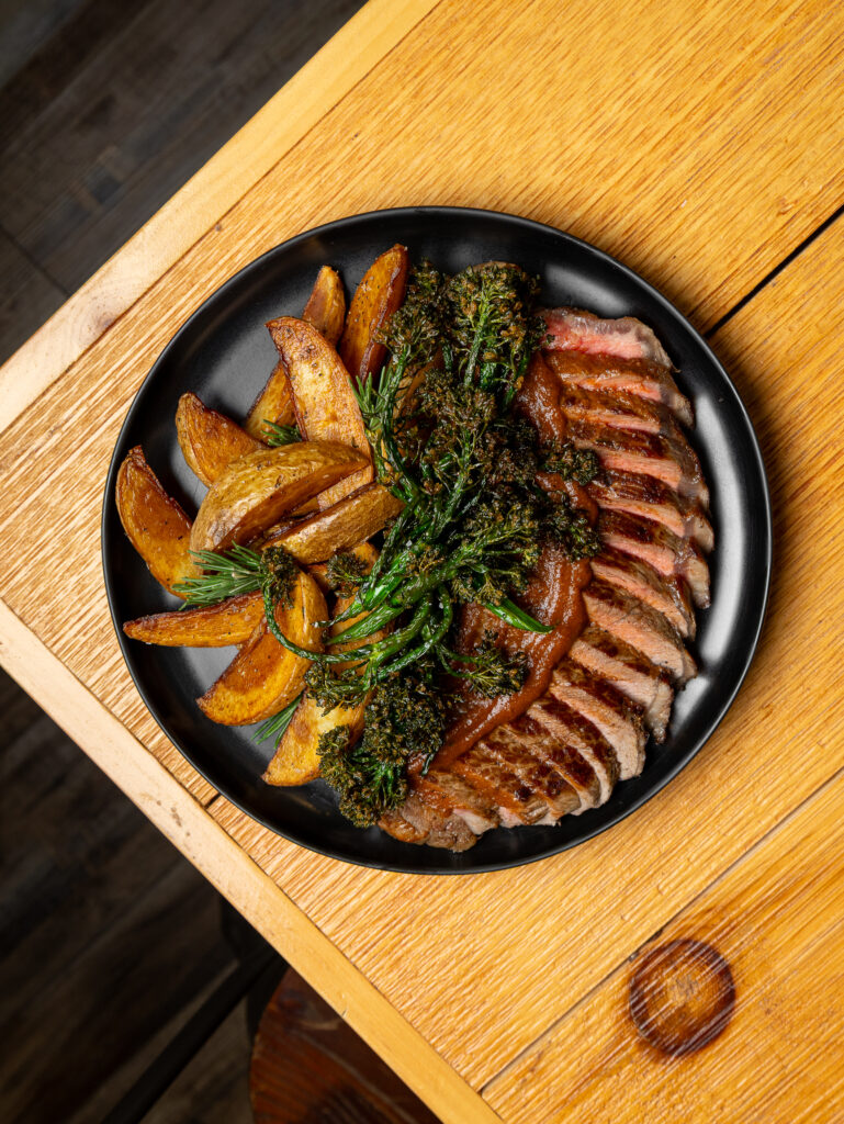 A cooked steak served with crispy potato wedges on a plate.