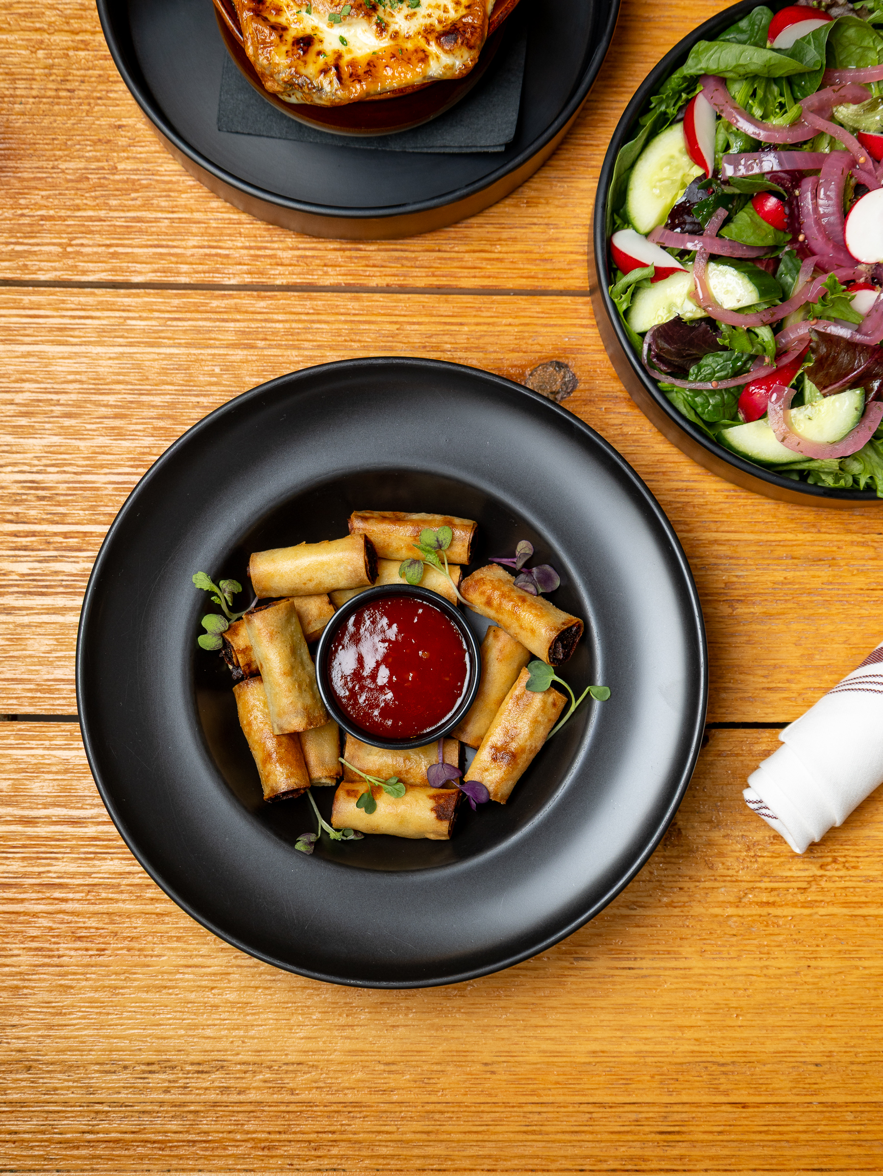 A fresh salad served on a plate with a side dish of ketchup sauce.