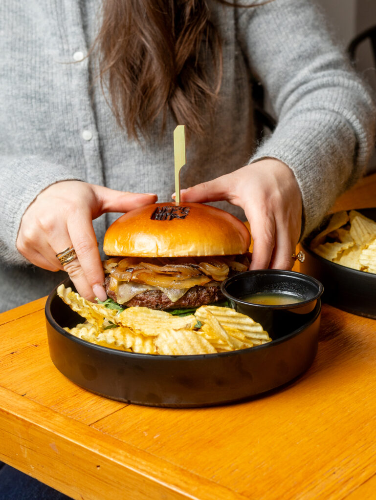 A close-up shot of the Hef’s Hut Bar & Grill menu showing a burger with chips.