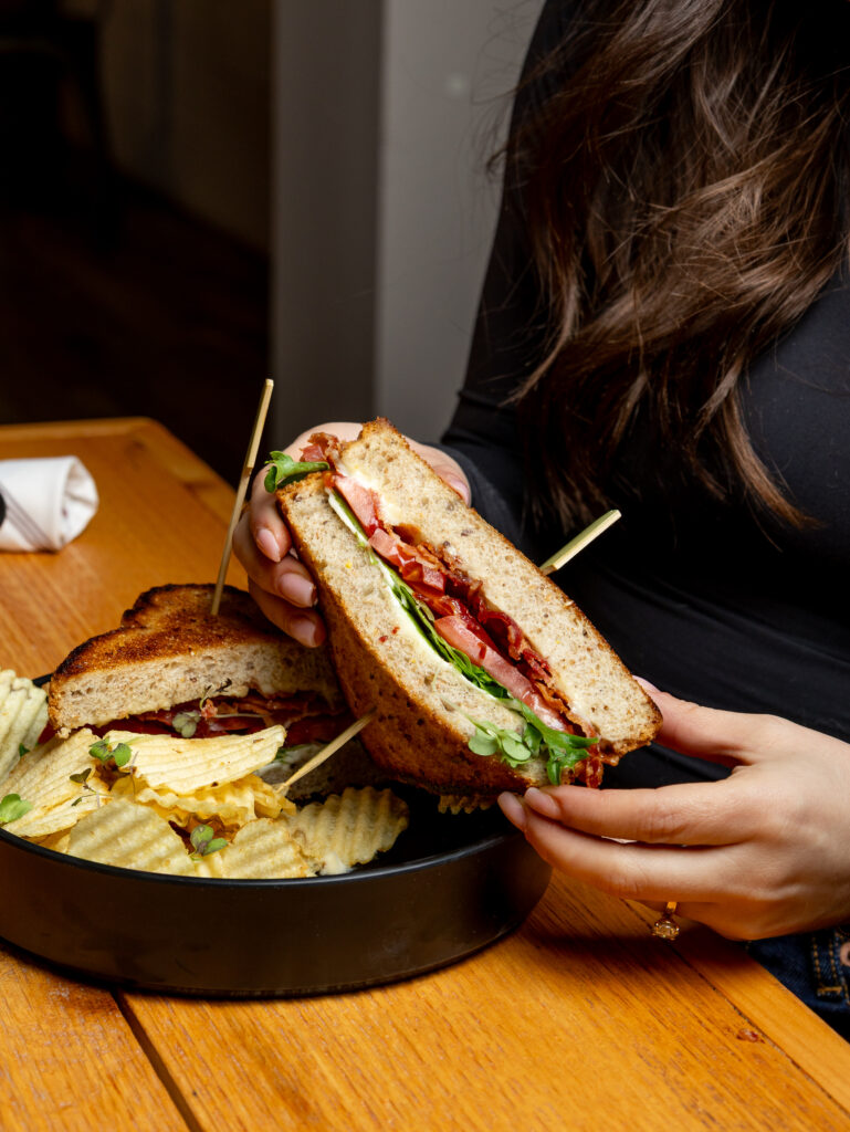 A close-up of a Hef’s Hut burger cut in half, showing the filling and served with chips.